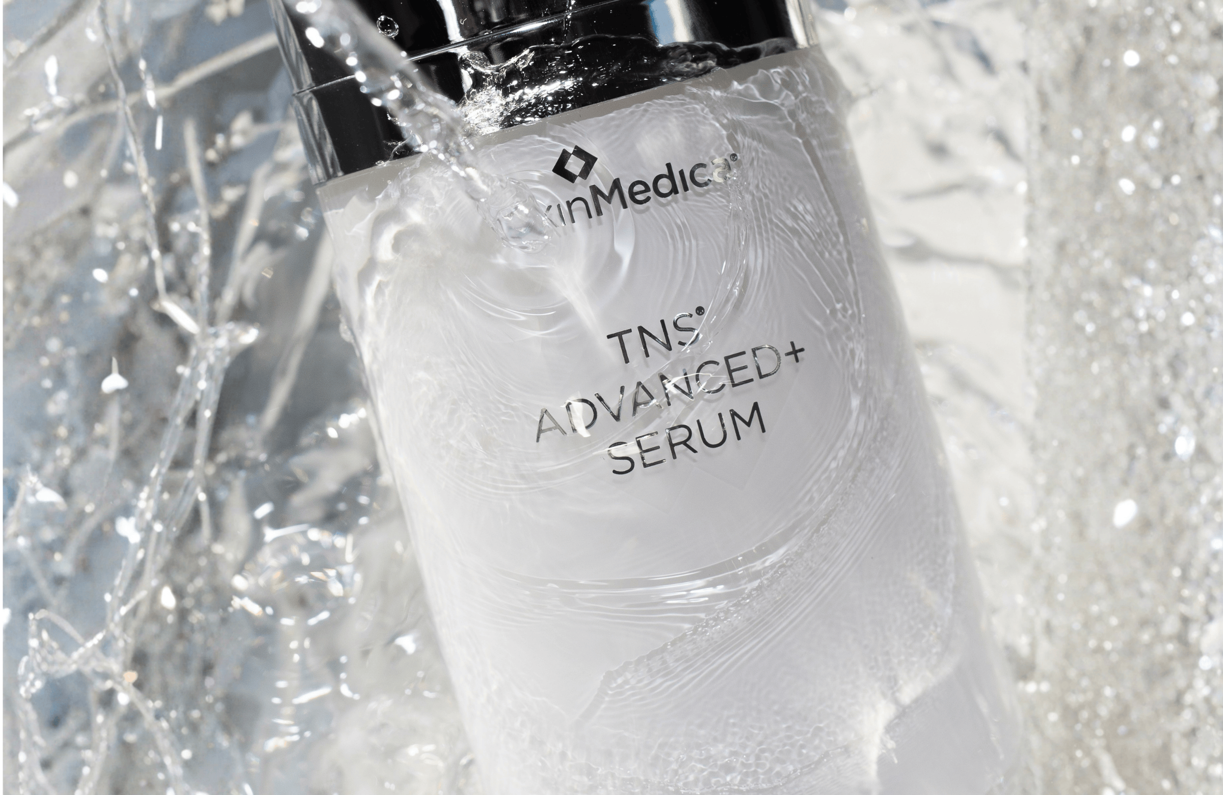 SkinMedica TNS Advanced Serum bottle with water droplets on a textured white background